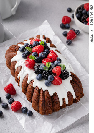 Chocolate pound cake topped with cream cheese glaze and berries Chocolate pound cake topped with cream cheese glaze and berries 106154962