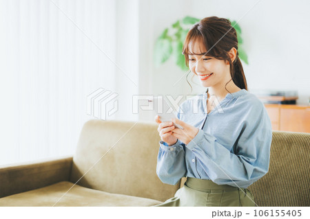 ソファに座ってスマホを見る女性 106155405