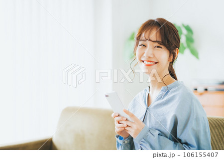 ソファに座ってスマホを持つ女性 106155407
