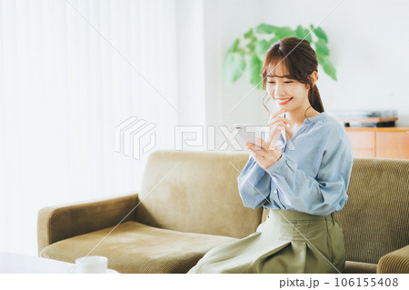 ソファに座ってスマホを見る女性 106155408