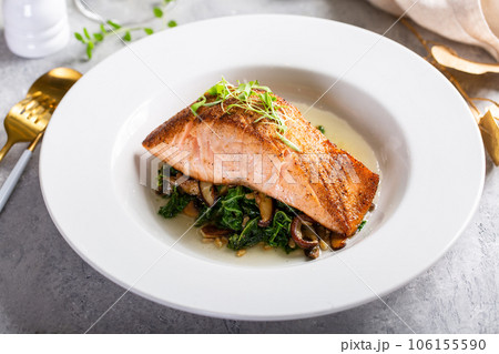 Salmon fillet served with sauteed greens and mushrooms 106155590
