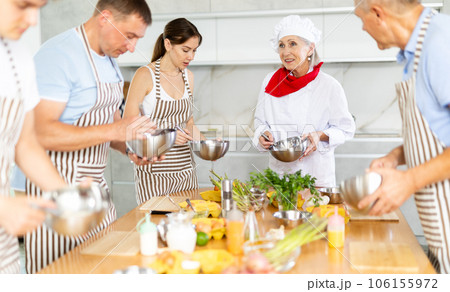 Elderly woman teaching cooking to group of people Elderly woman teaching cooking to group of people 106155972