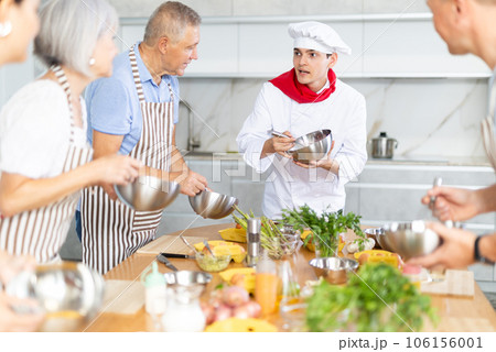 Young professional chef leading culinary courses to group of people 106156001