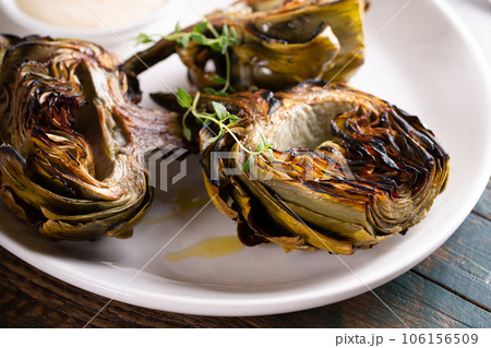 Grilled artichokes with a dipping sauce on a plate Grilled artichokes with a dipping sauce on a plate 106156509