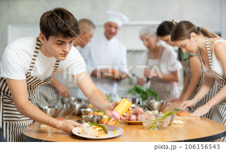 Enthusiastic guy seasoning finished dish with sauce at culinary class 106156543