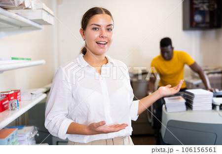 Print shop employee invites a customer to come inside 106156561