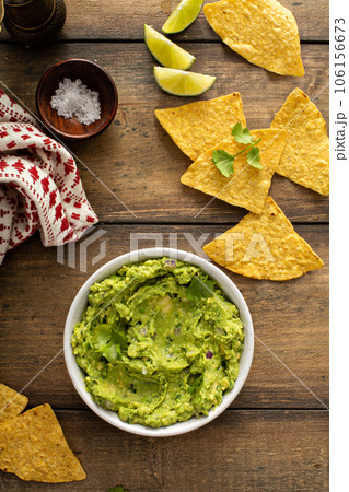 Chunky homemade guacamole in a bowl with tortilla chips Chunky homemade guacamole in a bowl with tortilla chips 106156673