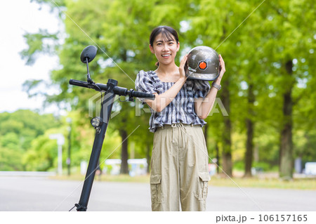 電動キックボード運転の交通安全のためヘルメットを被る若くて可愛い女性|電動キックボードイメージ 電動キックボード運転の交通安全のためヘルメットを被る若くて可愛い女性|電動キックボードイメージ 106157165