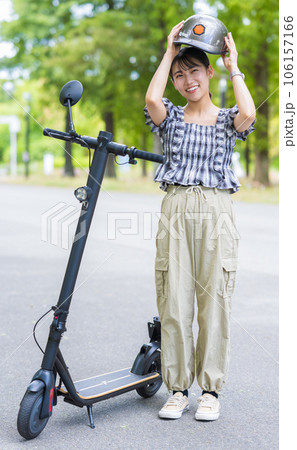 電動キックボード運転の交通安全のためヘルメットを被る若くて可愛い女性｜電動キックボードイメージ 106157166