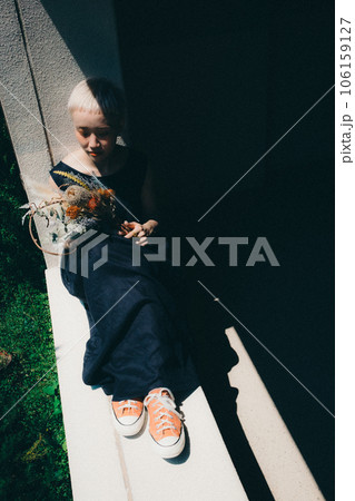 窓辺にドライフラワーを持って座る女性 窓辺にドライフラワーを持って座る女性 106159127