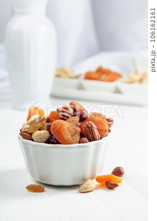 Dried fruits and assorted nuts on a white table. Dried fruits and assorted nuts on a white table. 106162161