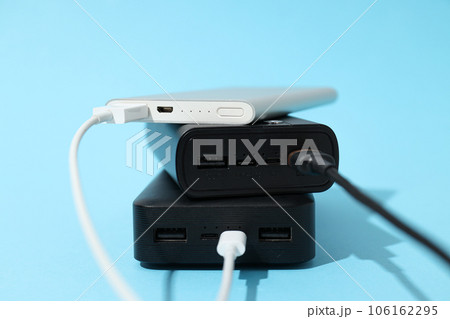 Powerbanks with cords on blue background, close up Powerbanks with cords on blue background, close up 106162295