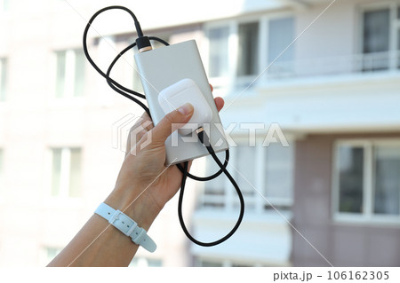 Powerbank and wireless headphones in female hands outdoors Powerbank and wireless headphones in female hands outdoors 106162305