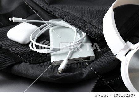 Powerbank and wireless headphones in backpack pocket on white background, close up 106162307