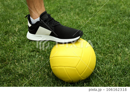 Male legs in sneakers and volleyball ball on grass 106162318