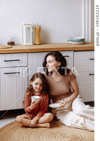 Mother and daughter drinking tea in the kitchen Mother and daughter drinking tea in the kitchen 106163210