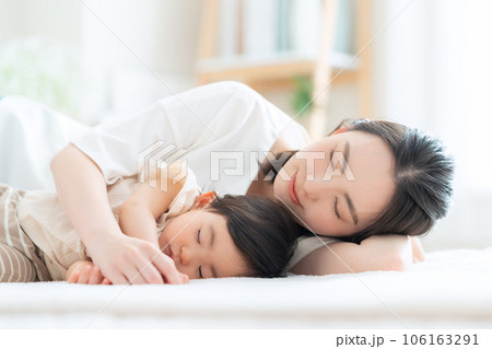 リビングで昼寝をする赤ちゃんと若いお母さん 106163291