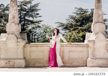 Woman park. Happy woman in classic white suit standing confidently looking away in old city park Woman park. Happy woman in classic white suit standing confidently looking away in old city park 106163378