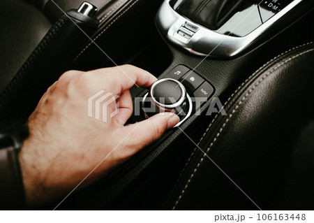 A driver hand is turning button of car radio, human hand adjust a button switch 106163448