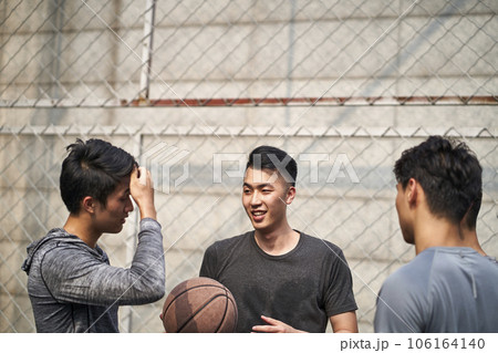 young asian basketball players chatting talking relaxing on outdoor court young asian basketball players chatting talking relaxing on outdoor court 106164140