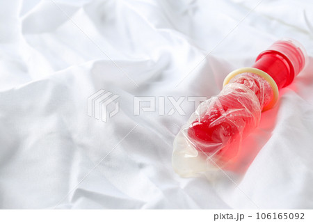 Condom on a red bottle with lubricant on a white background, place for text Condom on a red bottle with lubricant on a white background, place for text 106165092