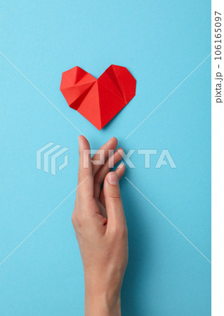 Red paper heart with a hand on a blue background. Blood donation Red paper heart with a hand on a blue background. Blood donation 106165097