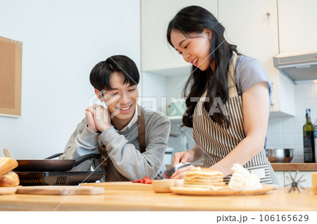 A lovely Asian couple enjoys making pancakes in the kitchen together. cooking date A lovely Asian couple enjoys making pancakes in the kitchen together. cooking date 106165629