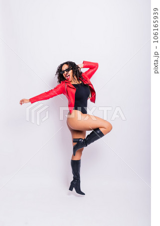 African American curvy female in black bodysuit and jacket on red and white background in studio 106165939