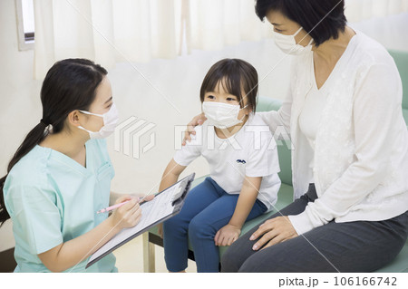 病院の待合室で問診をする看護師と子供の患者と付添いの祖母 106166742