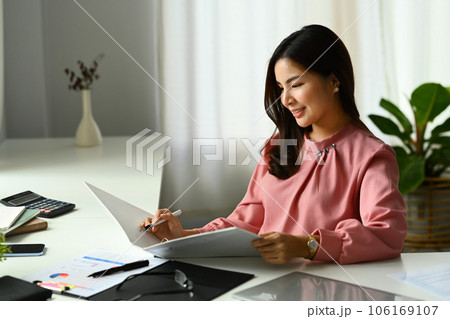 Beautiful asian female accountant checking report, financial data or bookkeeping in office 106169107