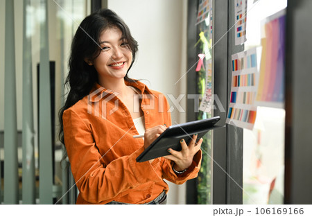 Portrait of confident female designer standing by glass window with color swatch samples chart 106169166
