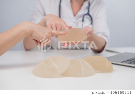 Caucasian woman and plastic surgeon touching and choosing breast implants. Caucasian woman and plastic surgeon touching and choosing breast implants. 106169211