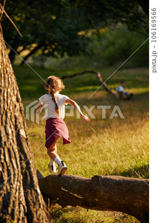 Little active child, girl in casual clothes running, playing in meadow in forest on warm sunny day Little active child, girl in casual clothes running, playing in meadow in forest on warm sunny day 106169566