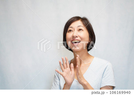 上を向いて笑顔で拍手する中年女性 106169940
