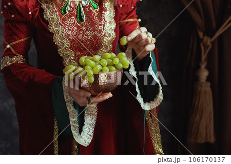Closeup on medieval queen in red dress with plate of grapes 106170137
