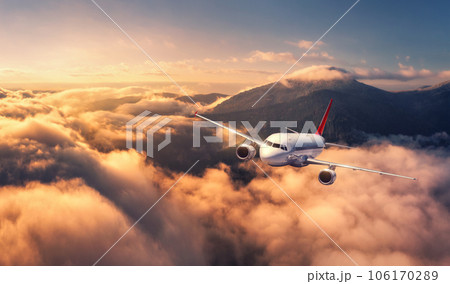 Airplane is flying above mountain peak in orange low clouds Airplane is flying above mountain peak in orange low clouds 106170289