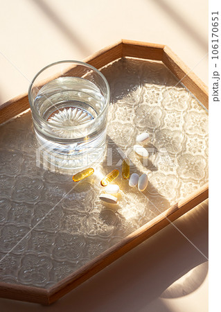 Various dietary supplement and glass of water. Wellbeing and health care concept. Various dietary supplement and glass of water. Wellbeing and health care concept. 106170651