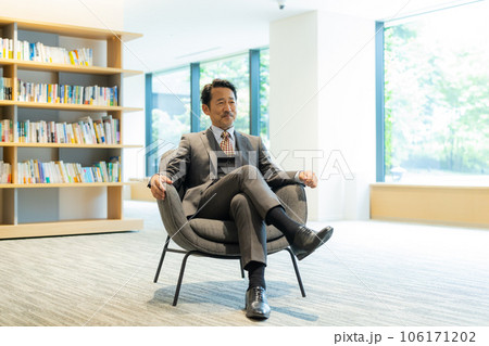 椅子に座って語るスーツの男性 106171202