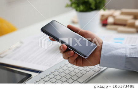 A businessman holds a new smartphone in 106173499