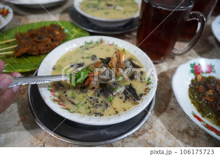 A bowl of Medan style soto or soup with a combination of beef, shrimp, and chicken, along with potato slices in a creamy broth A bowl of Medan style soto or soup with a combination of beef, shrimp, and chicken, along with potato slices in a creamy broth 106175723