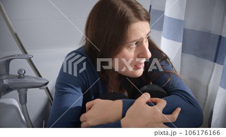 Scared and frightened woman hiding in bathroom. Concept of domestic violence victim, stress, danger at home, fear. 106176166