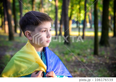Worried teenager patriot wear blue yellow Ukrainian flag on his shoulders. Spring nature background. Ukraine national symbol. Patriotism Worried teenager patriot wear blue yellow Ukrainian flag on his shoulders. Spring nature background. Ukraine national symbol. Patriotism 106176539