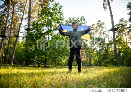 Pray for Ukraine. boy with Ukrainian flag running the summer park. Little kid waving national flag praying for peace. Happy child celebrating Independence Day Pray for Ukraine. boy with Ukrainian flag running the summer park. Little kid waving national flag praying for peace. Happy child celebrating Independence Day 106176602