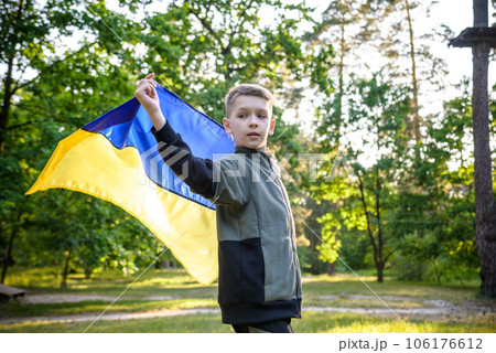 Pray for Ukraine. boy with Ukrainian flag running the summer park. Little kid waving national flag praying for peace. Happy child celebrating Independence Day Pray for Ukraine. boy with Ukrainian flag running the summer park. Little kid waving national flag praying for peace. Happy child celebrating Independence Day 106176612