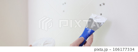 Builder or repairman with putty knife plastering white wall close up. Builder or repairman with putty knife plastering white wall close up. 106177334