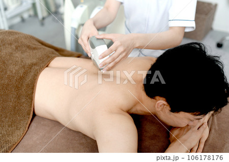 背中の脱毛施術をするセラピストと男性患者 106178176