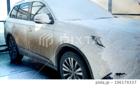 Closeup of applying foam on dirty car at washing service. Automobile care, transport cleaning, dirty car. 106178337