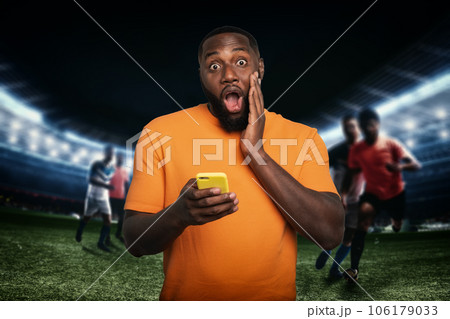 Man surprised by a soccer action with cell phone in his hand 106179033