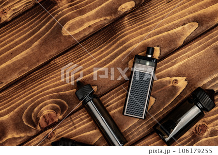Vape and vape juice bottles on brown wooden background Vape and vape juice bottles on brown wooden background 106179255