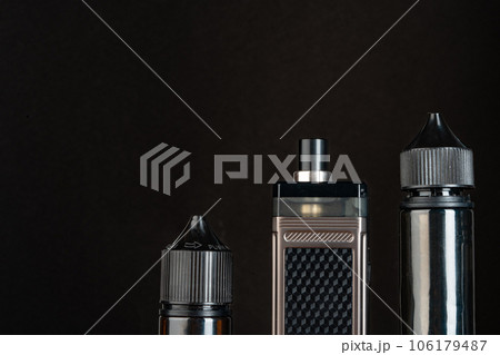 Vape and vape liquid bottles against black background Vape and vape liquid bottles against black background 106179487